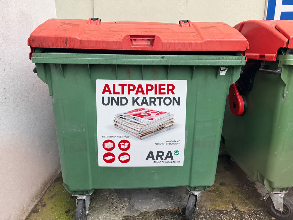 Altpapiercontainer in Österreich mit Aufkleber für Altpapier und Karton